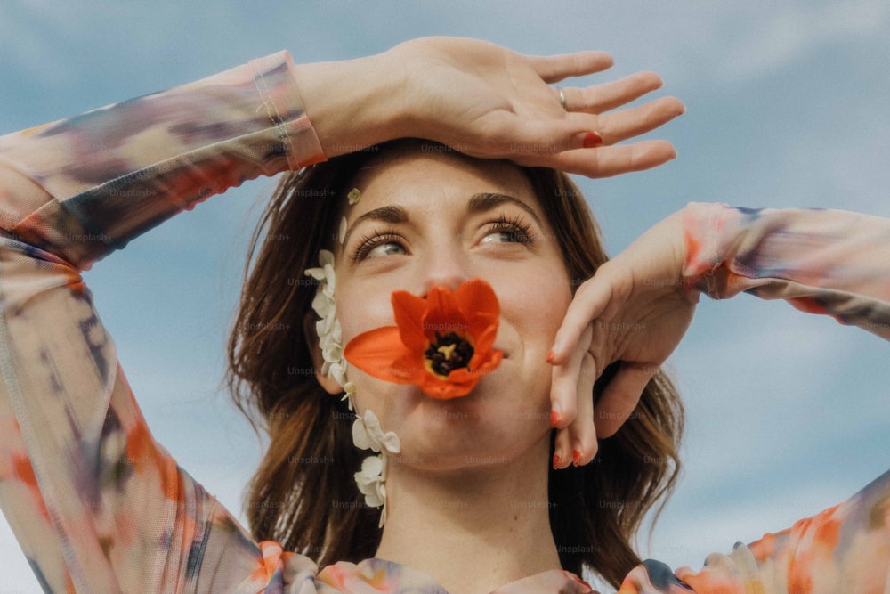 une femme tenant une fleur devant son visage