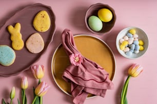 une table rose surmontée d’assiettes de nourriture et de fleurs