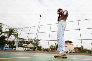 Un hombre parado en una cancha de tenis hablando por teléfono celular