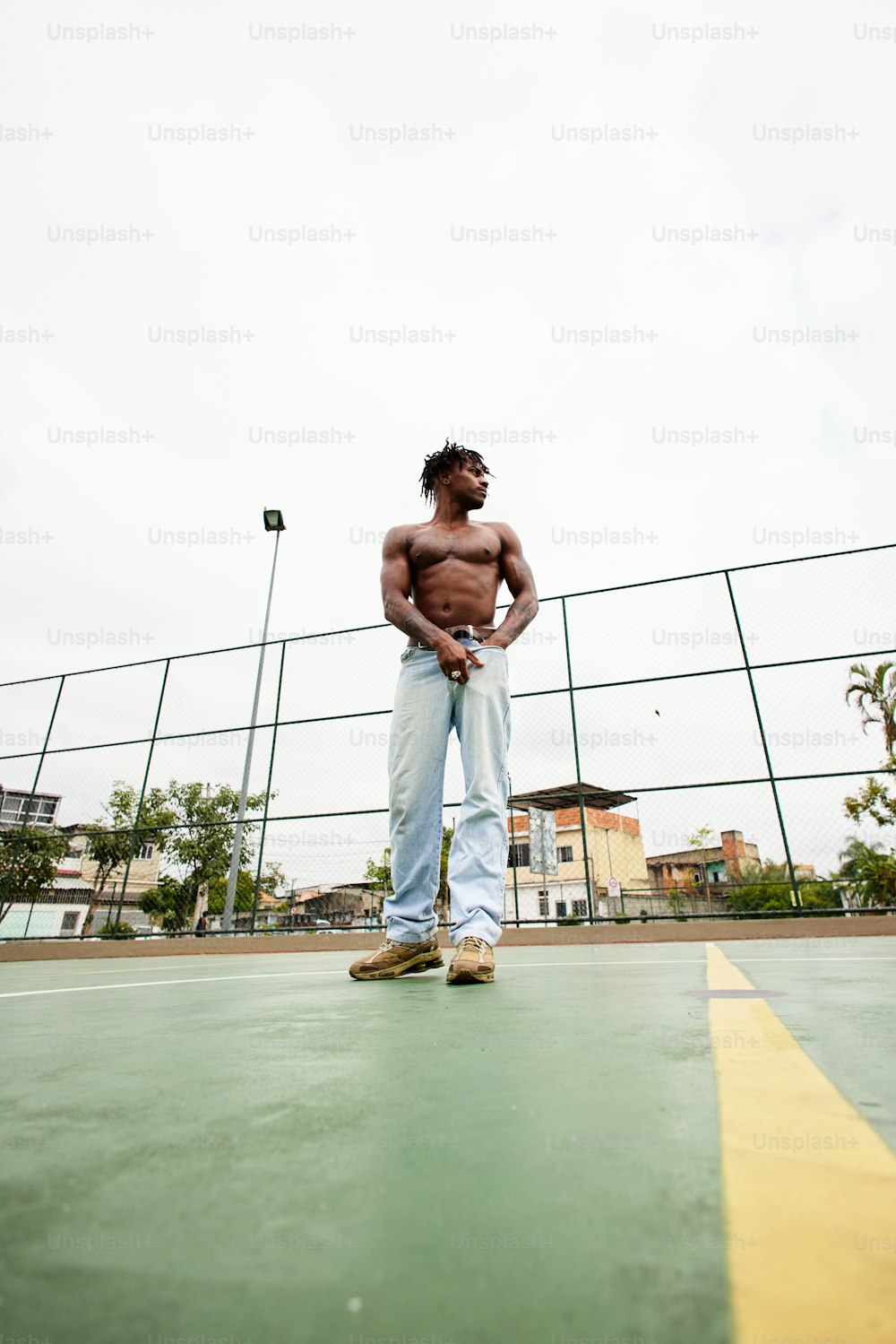a shirtless man standing on a tennis court