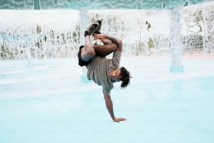 a man doing a handstand in front of a fountain