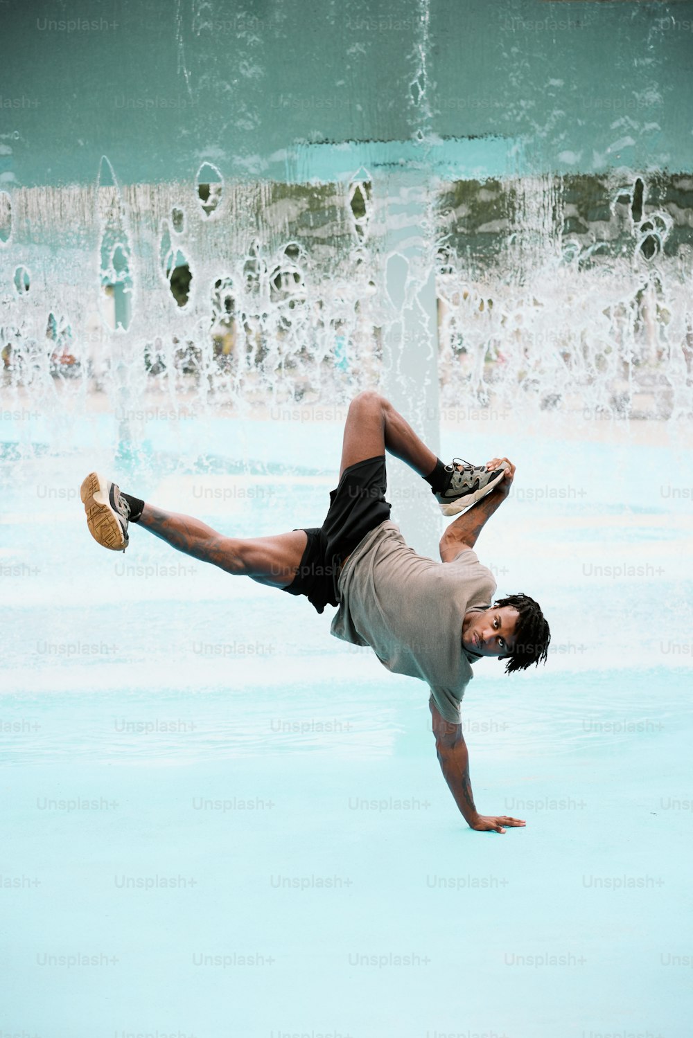 a man doing a handstand in front of a fountain