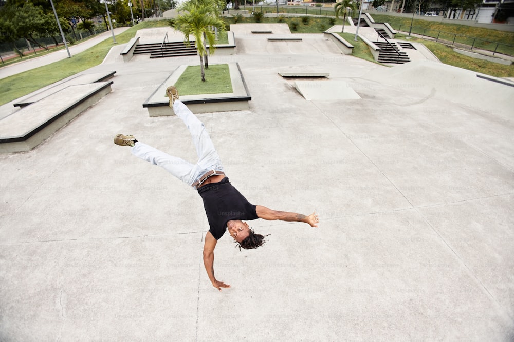 a man doing a handstand on a skateboard in a skate park