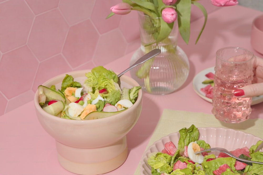 uma mesa rosa coberta com uma tigela de salada