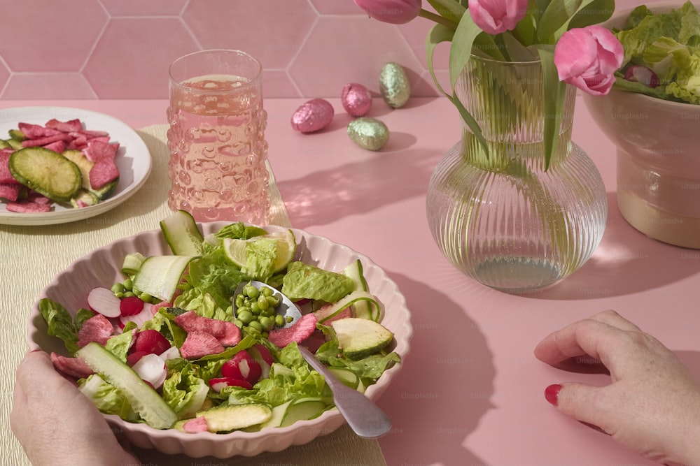 a person holding a bowl of salad on a table