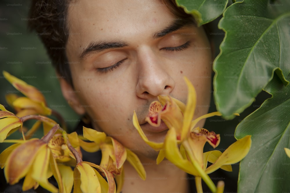 a man smelling a flower with his eyes closed