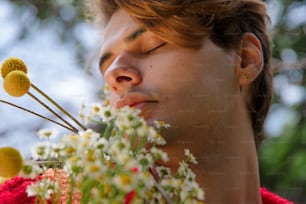 a young man is smelling a bunch of flowers