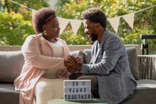 a man and woman sitting on a couch holding hands