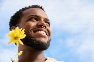 un hombre sosteniendo una flor frente a su cara