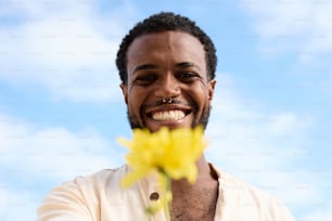 a man smiling and holding a flower in his hand