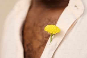 a man wearing a white shirt with a yellow flower pinned to his chest