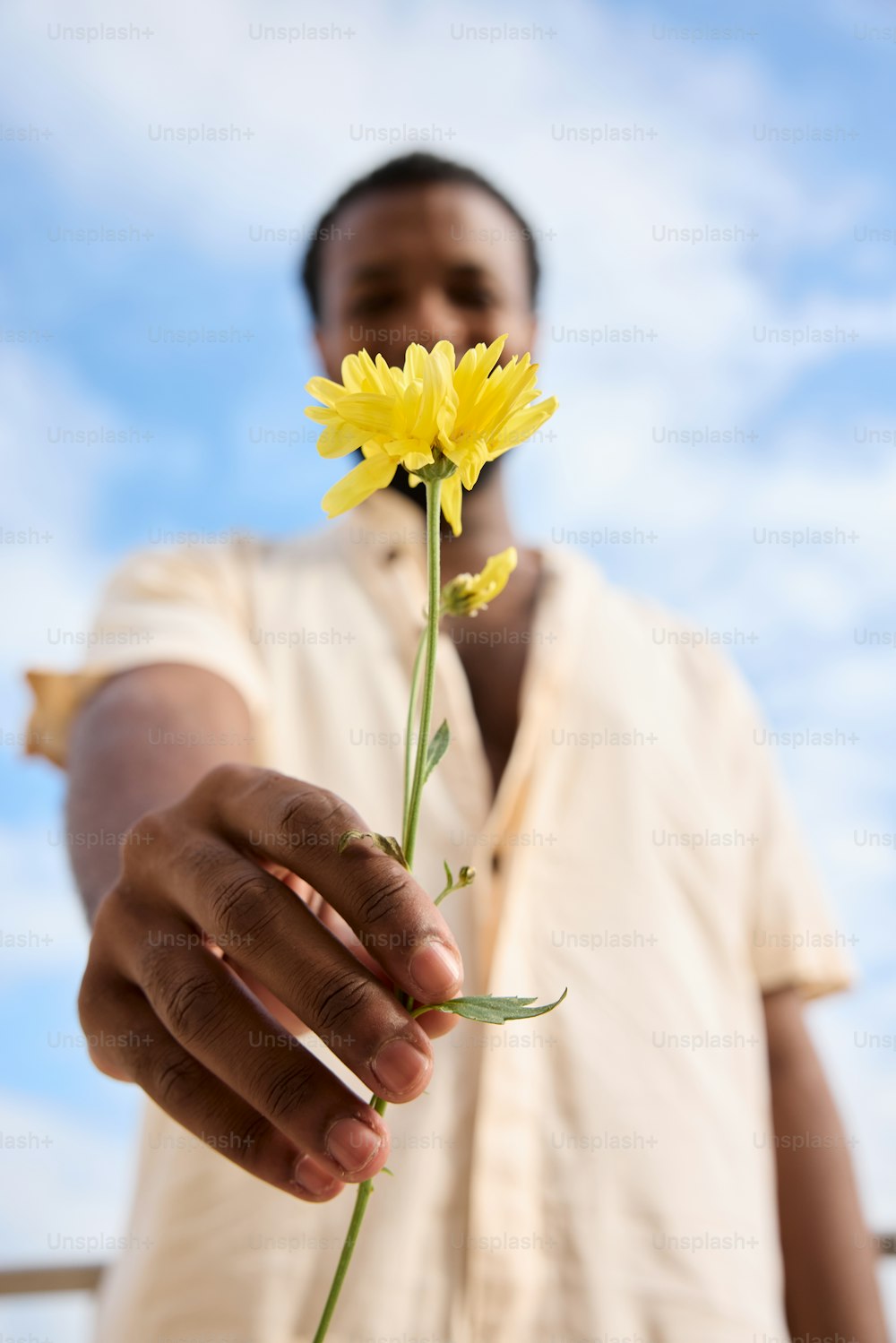 un hombre sosteniendo una flor amarilla en su mano
