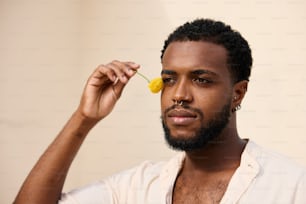 a man holding a flower up to his eye