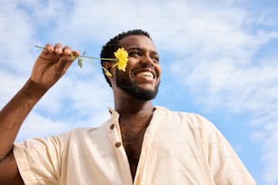 un hombre sosteniendo una flor frente a su cara