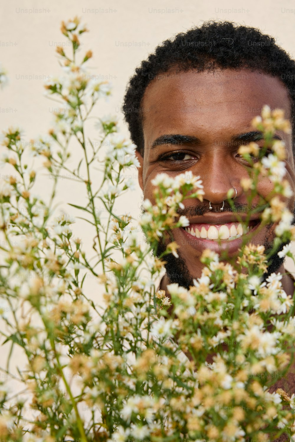 あごひげを生やした男性が笑顔で花に囲まれている