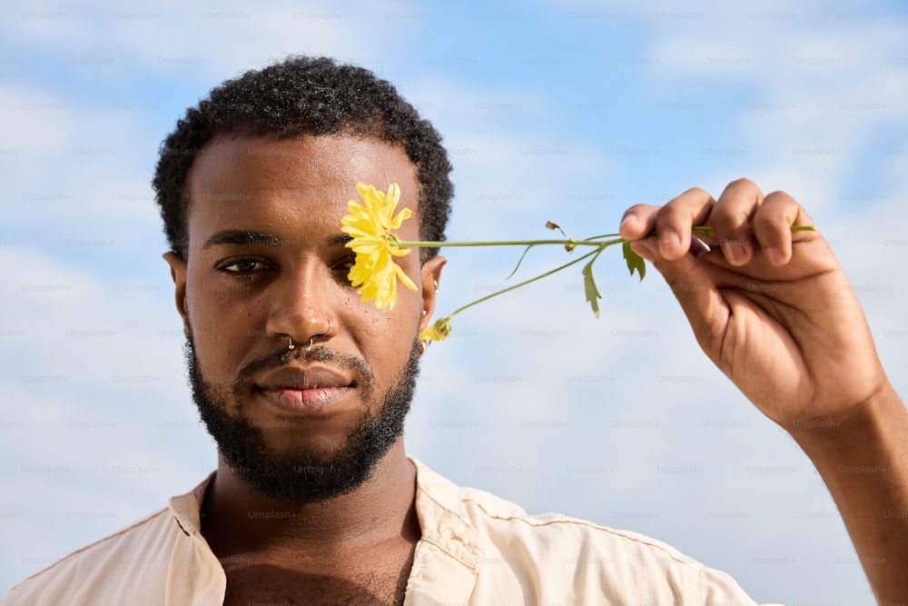 un homme tenant une fleur à son visage