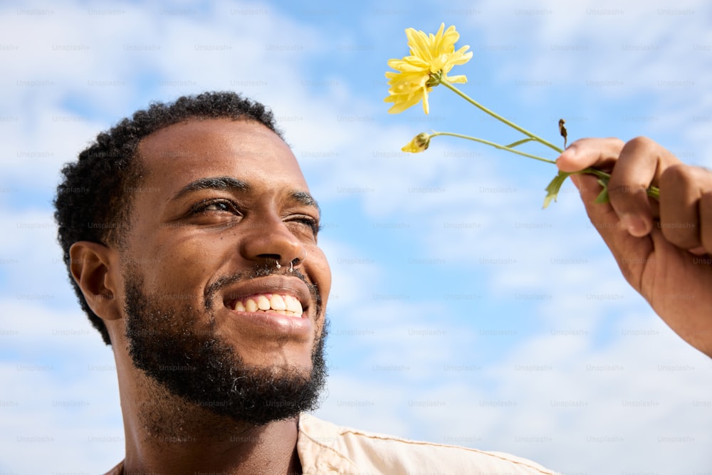 a man holding a flower up to his face