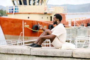 a man sitting on a ledge looking at his cell phone