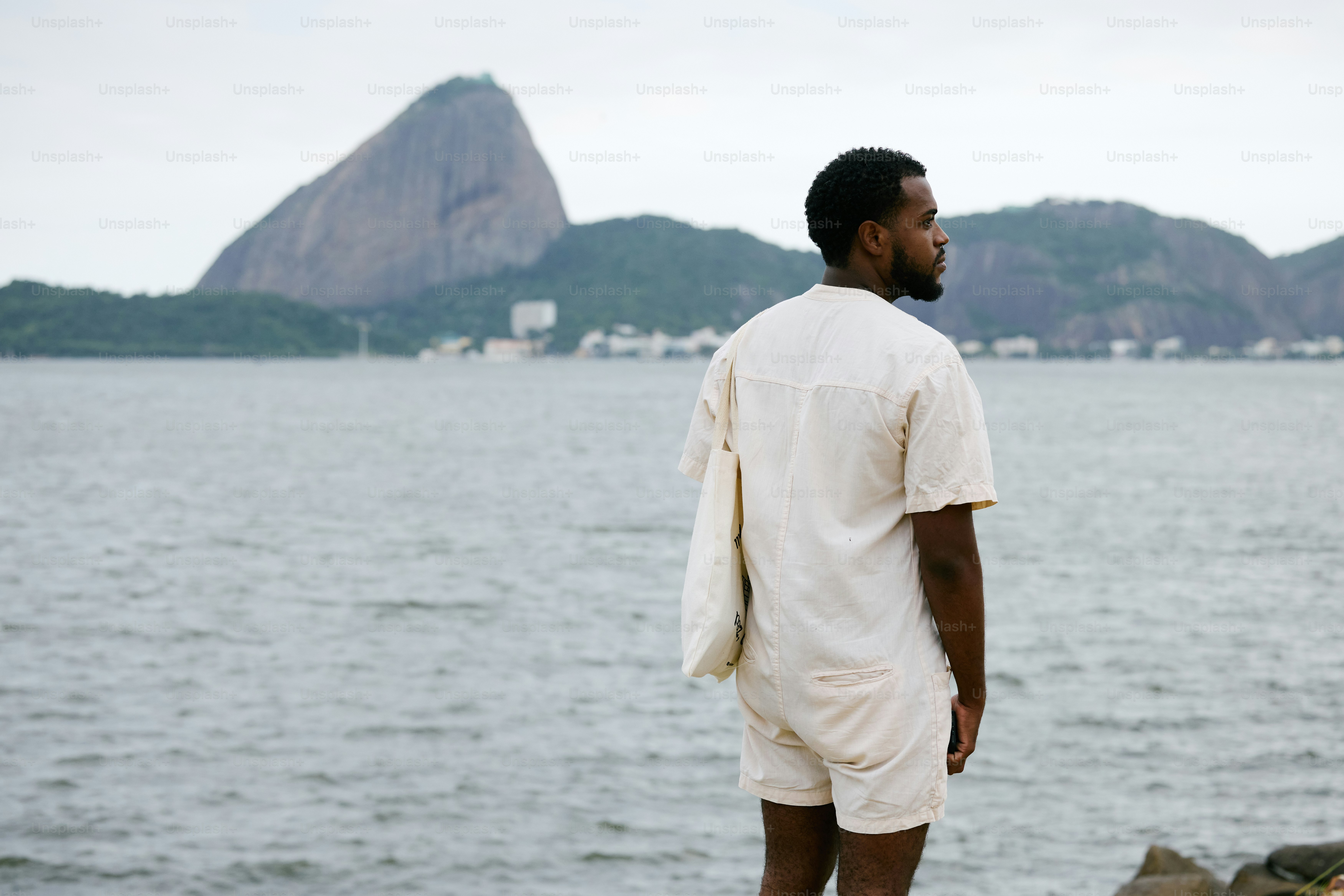 ein Mann, der auf einem Felsen steht und auf das Wasser schaut