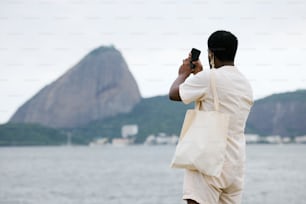 Un hombre tomando una foto de una montaña con un teléfono celular