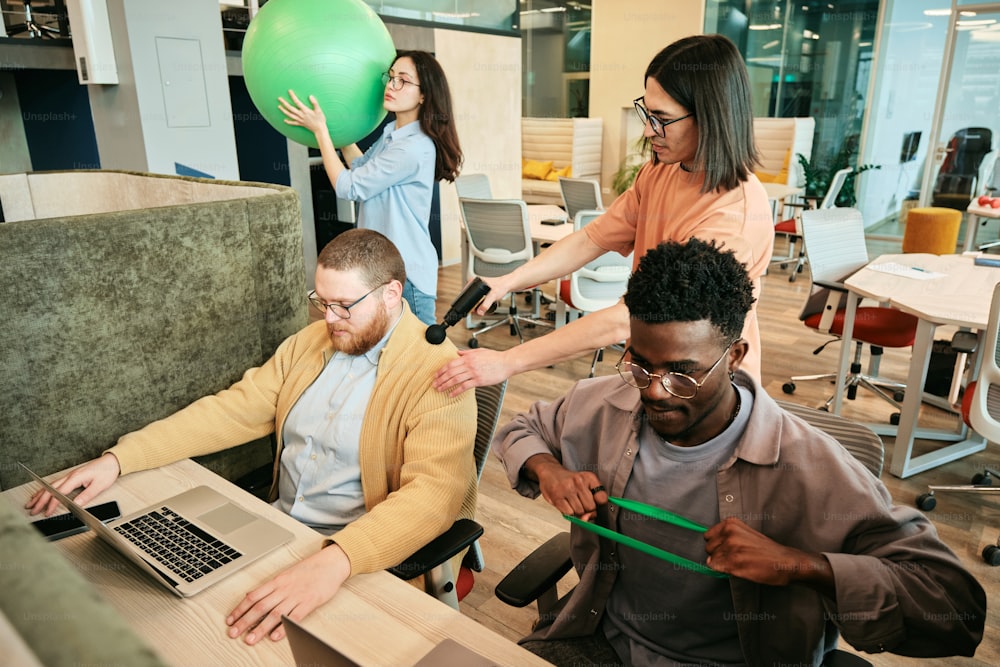 a group of people sitting around a table with laptops