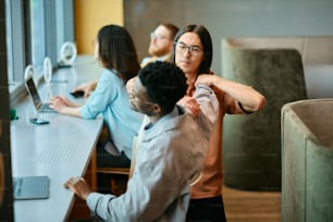 a group of people sitting at a table working on computers