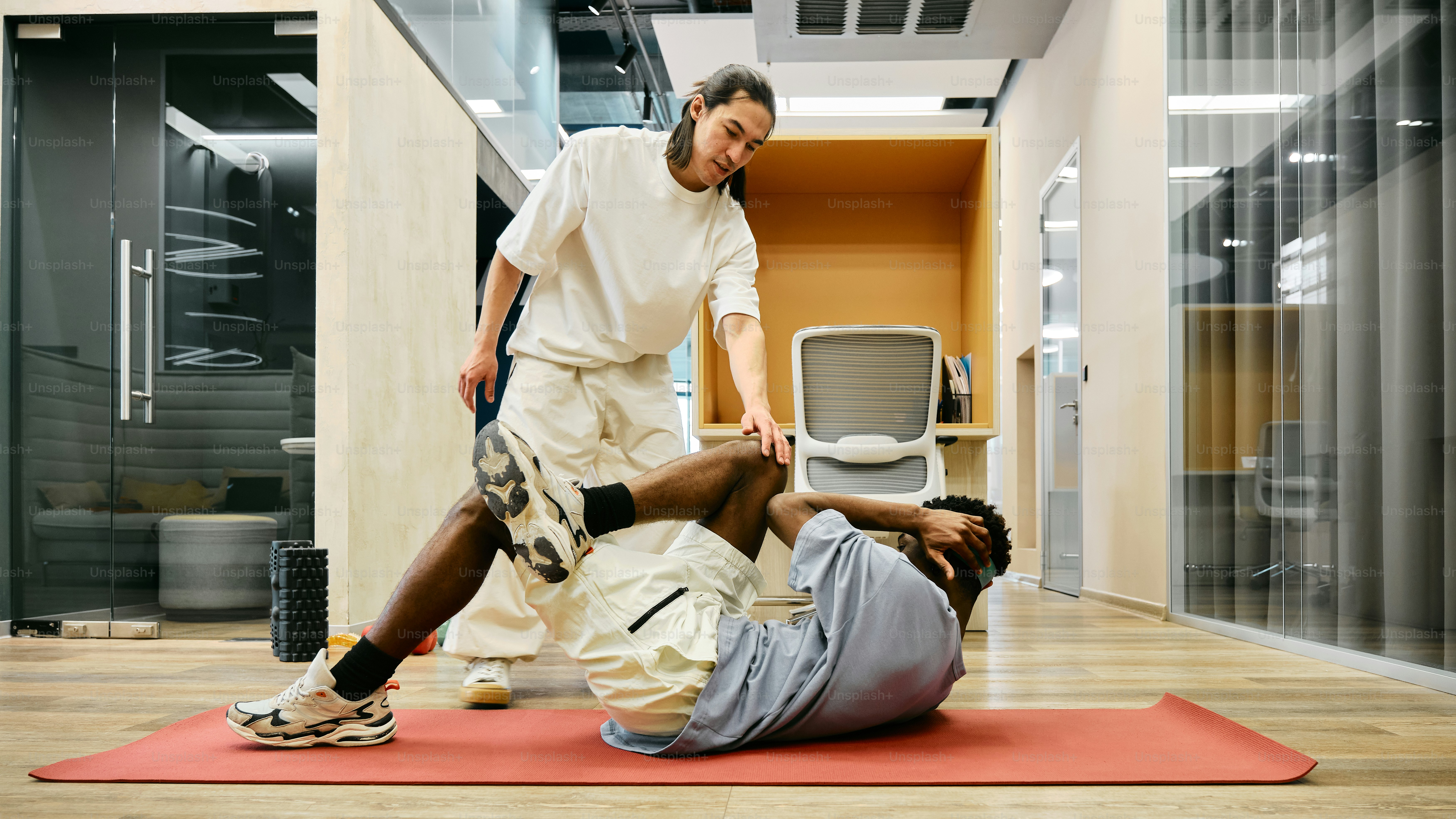 a man is doing a back stretch while another man watches