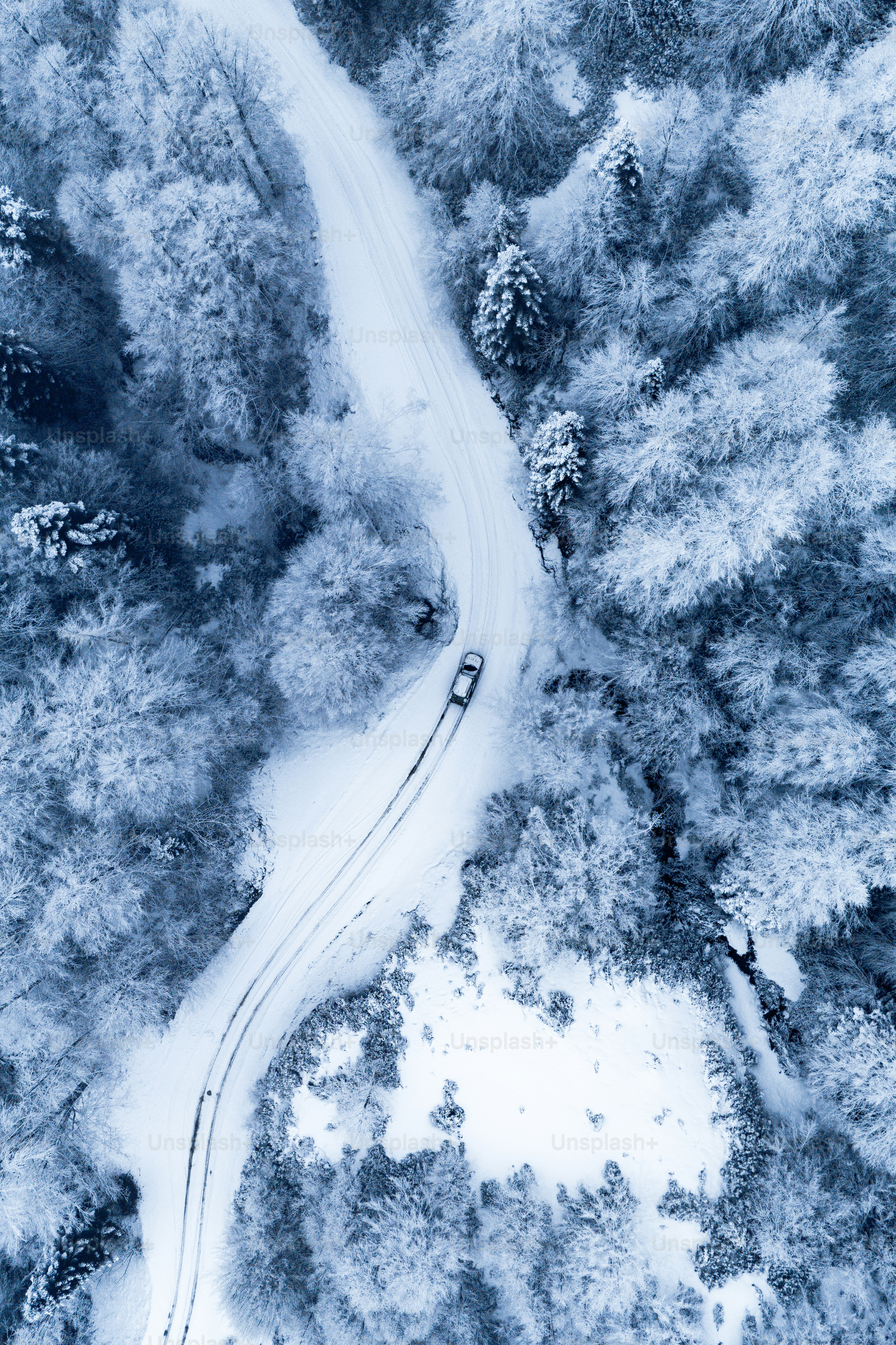 Una vista aérea de un coche conduciendo por una carretera nevada