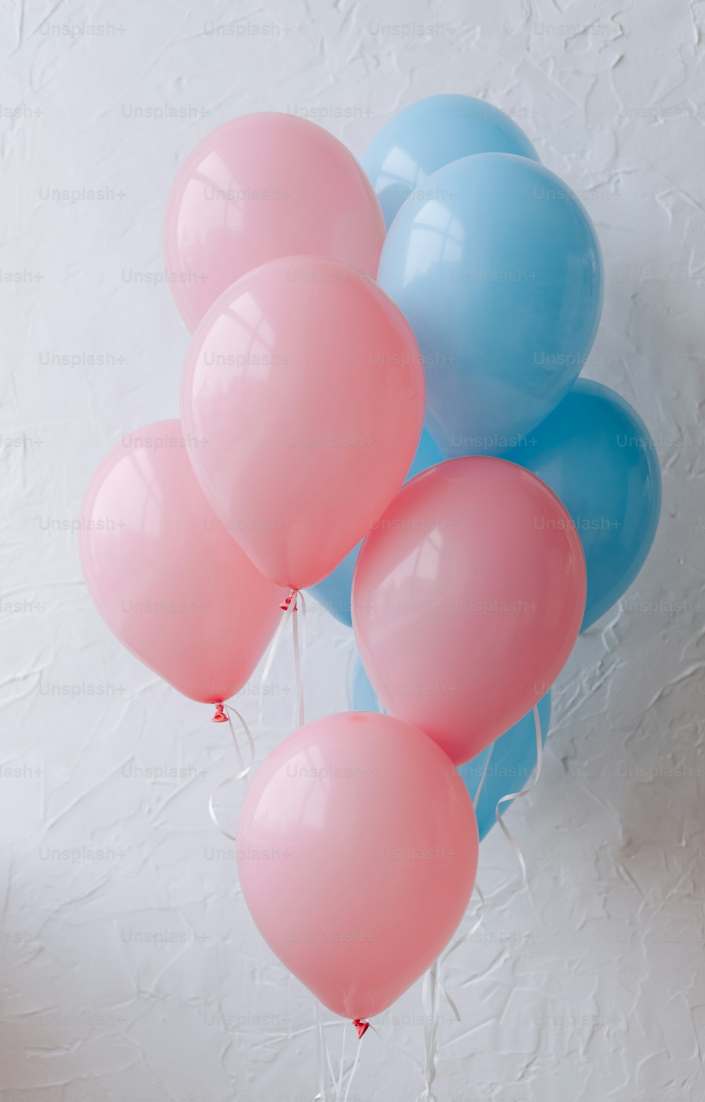 a bunch of blue and pink balloons on a wall