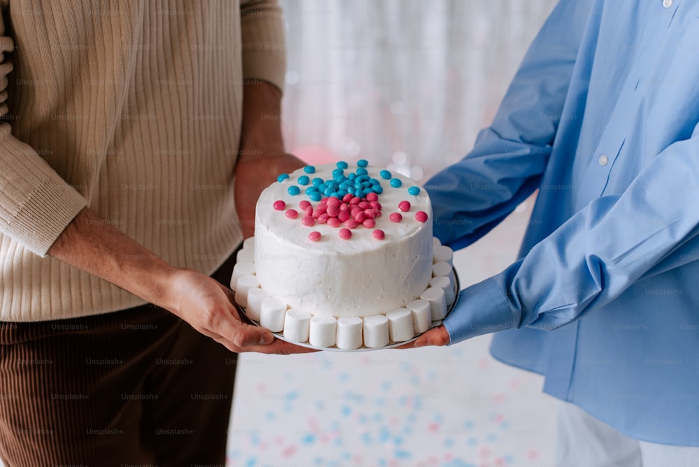 two people holding a cake with sprinkles on it