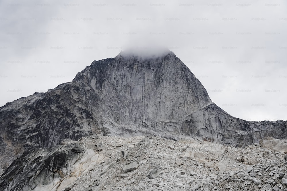 a very tall mountain covered in snow under a cloudy sky