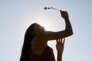 una mujer sosteniendo una flor hacia el cielo