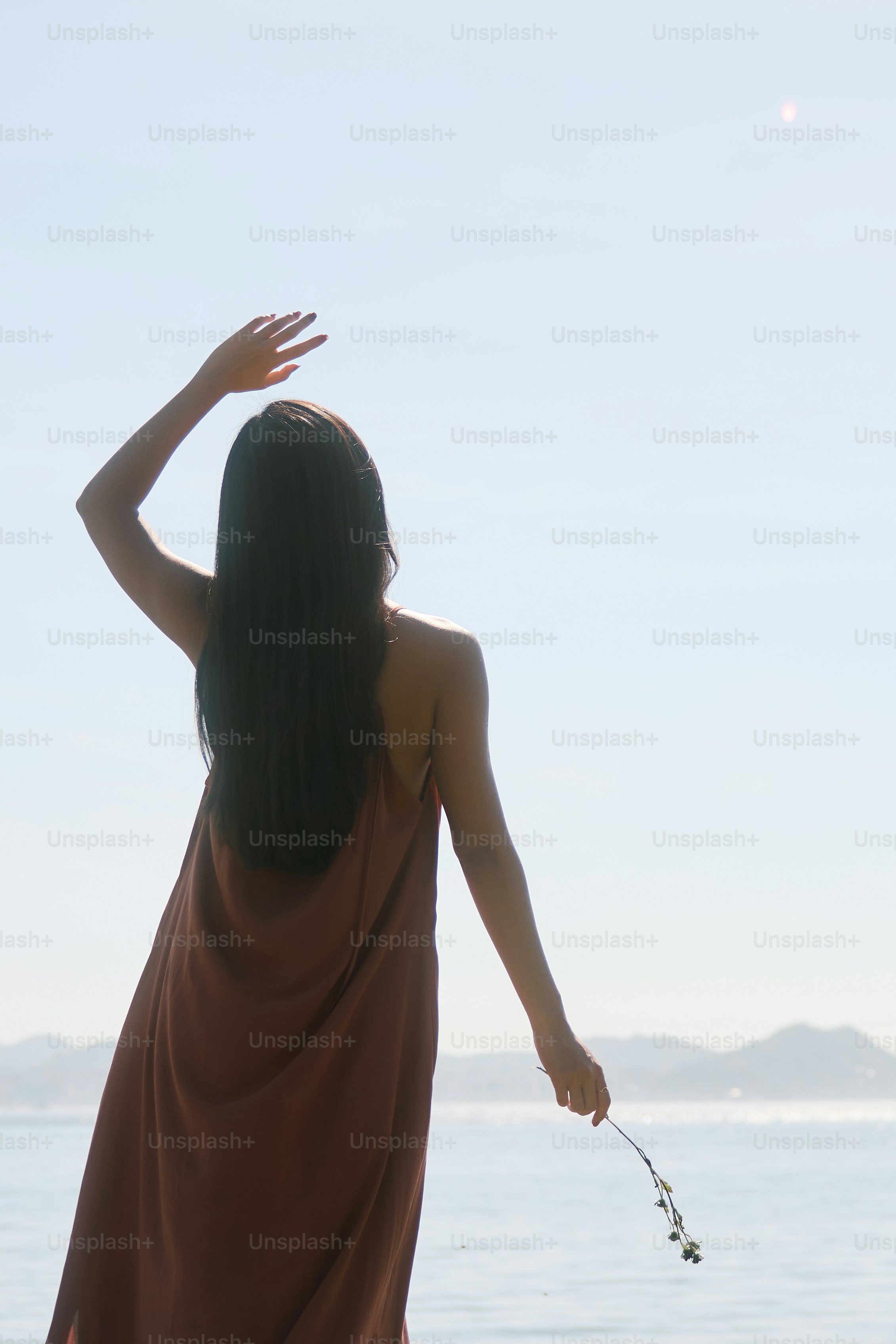 A woman in a brown dress standing on a beach photo – Flowers Image on ...