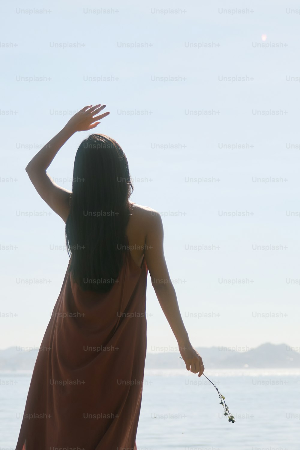 eine Frau in einem braunen Kleid steht an einem Strand