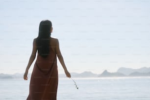 a woman in a long dress standing on a beach
