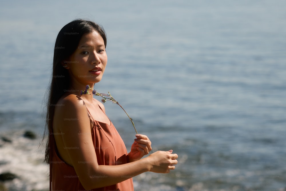 a woman standing on a beach holding a flower