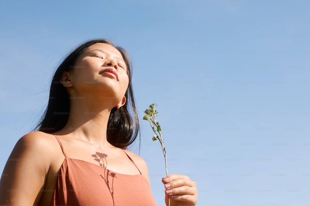 una mujer sosteniendo una flor hacia el cielo