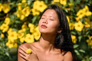 a woman with her eyes closed holding a yellow flower