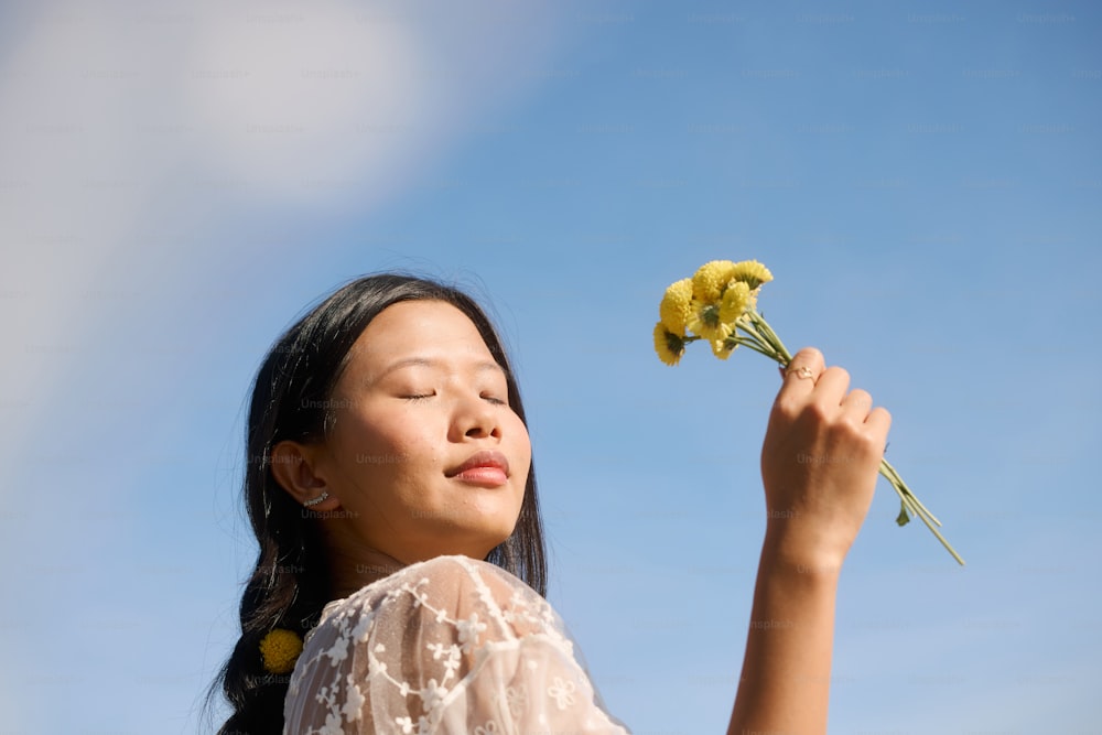 a woman holding a flower up to the sky
