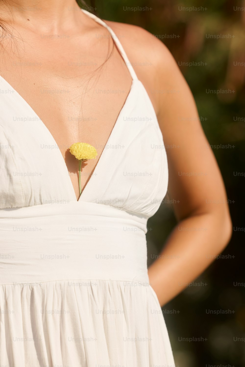 una donna in un vestito bianco che tiene un fiore giallo