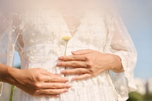 une femme en robe blanche tenant une fleur