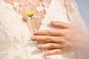 a woman's hand holding a yellow flower