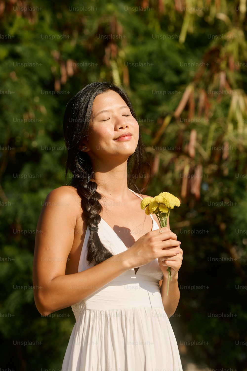 uma mulher em um vestido branco segurando uma flor amarela