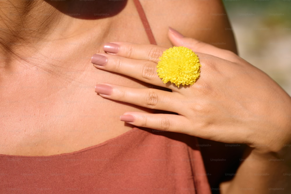 a woman wearing a ring with a yellow flower on it