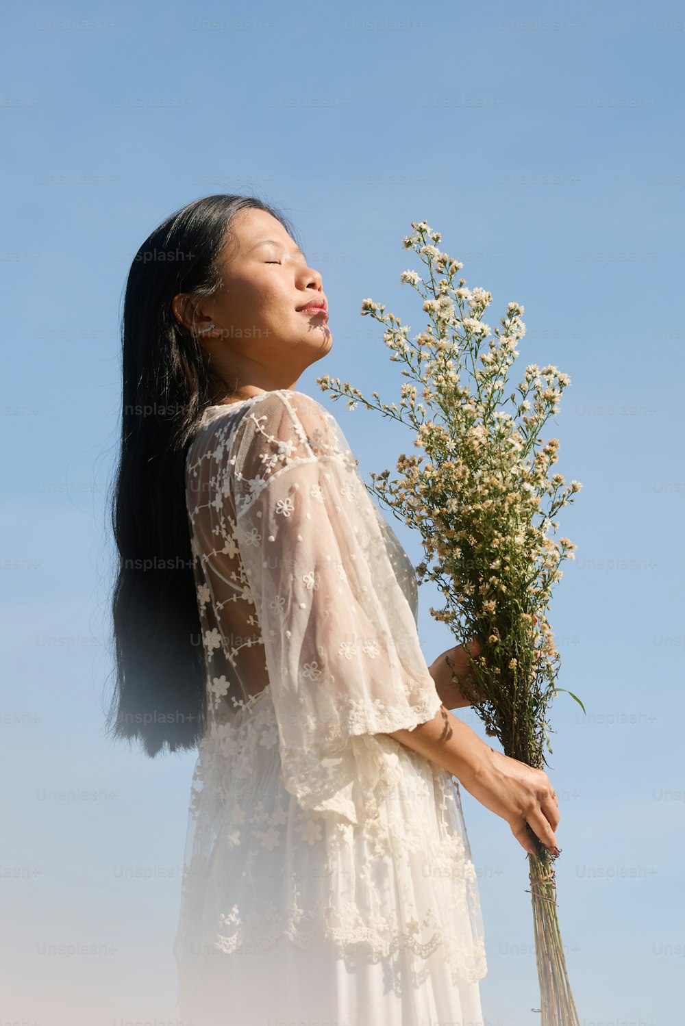 eine Frau in einem weißen Kleid mit einem Blumenstrauß in der Hand