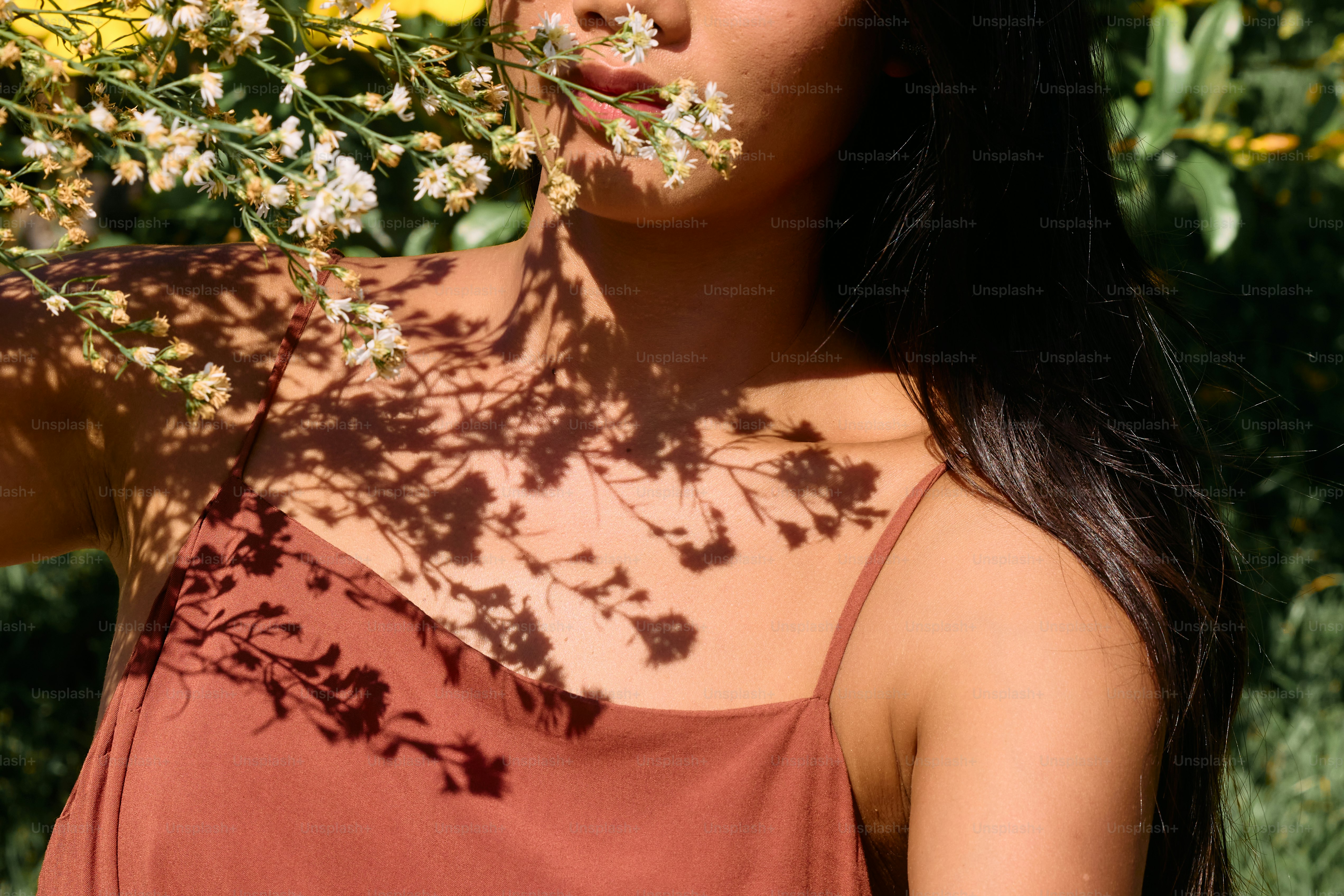 uma mulher com flores na boca em pé na frente de uma árvore