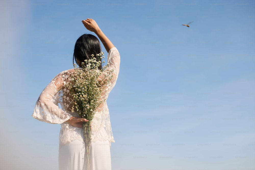 una mujer con un vestido blanco sosteniendo un ramo de flores