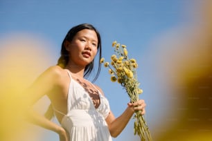 a woman in a white dress holding a bunch of flowers