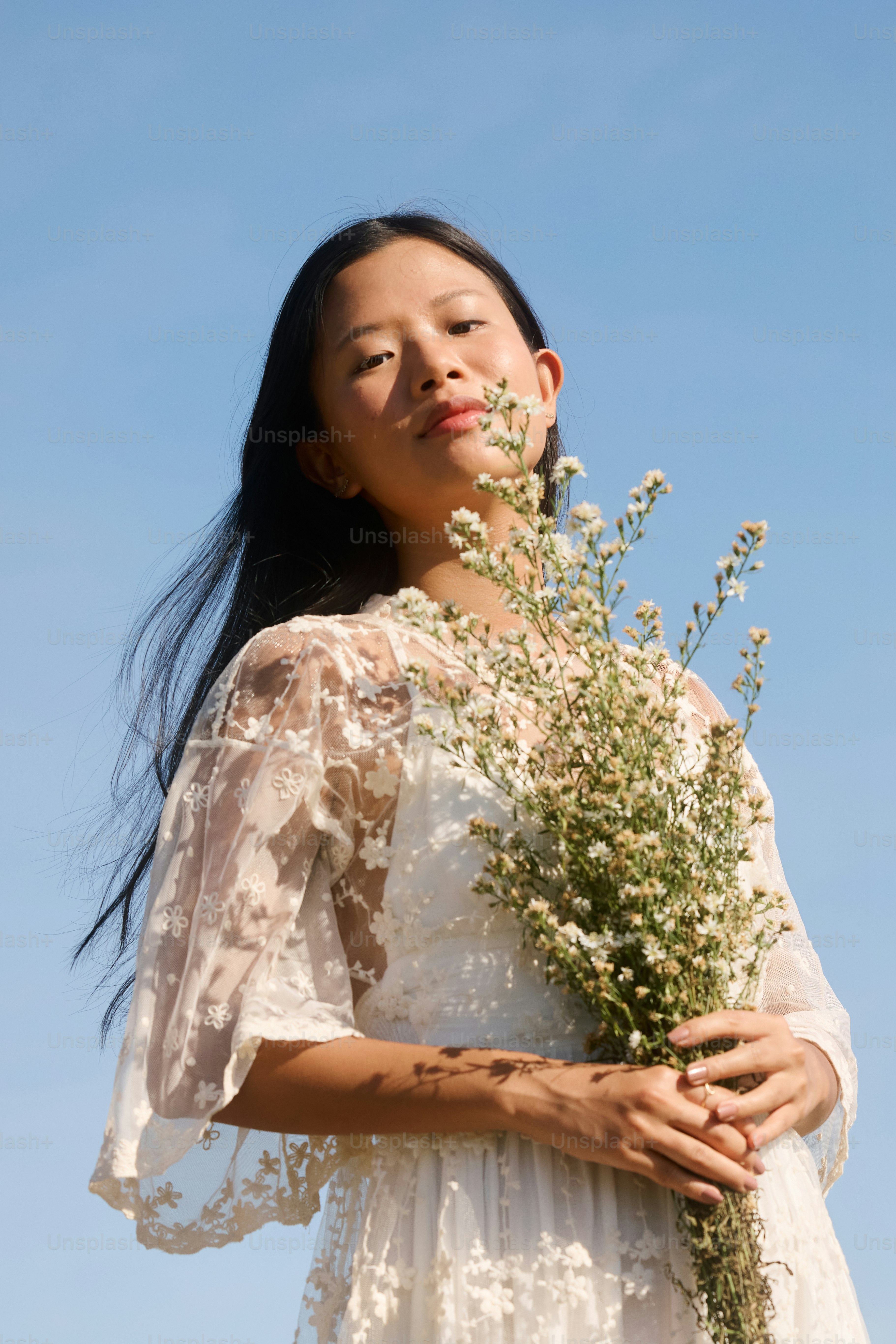A woman in a white dress holding a bouquet of flowers photo – Spring ...