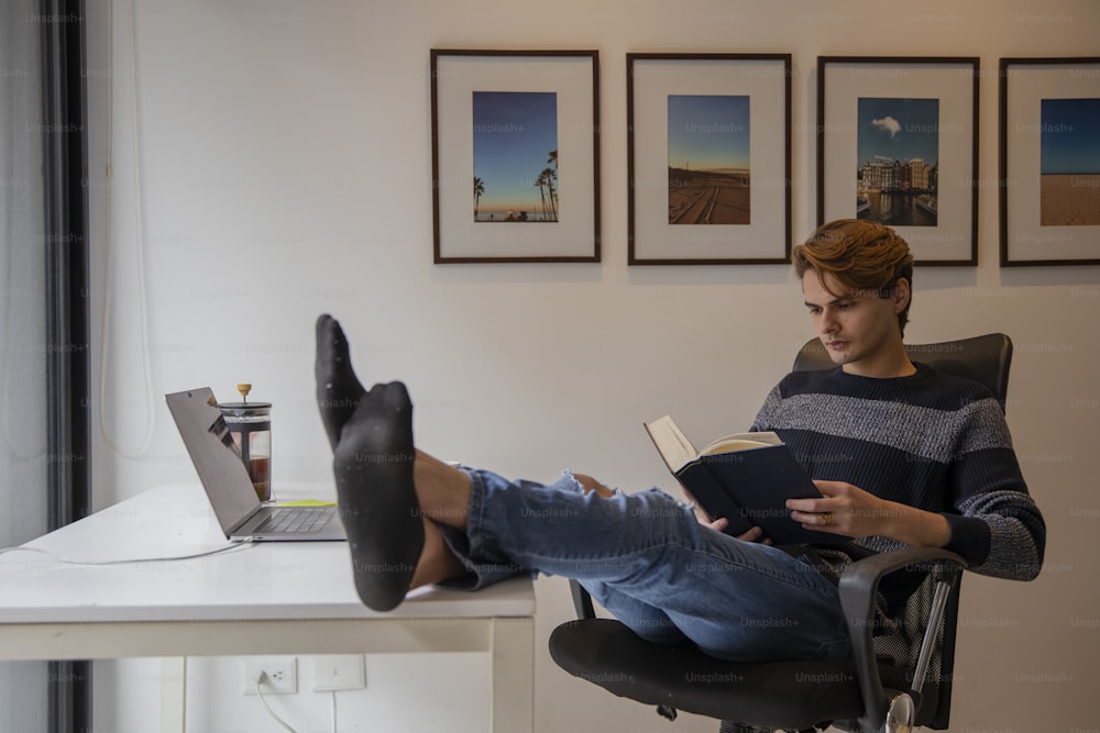 ein Mann, der auf einem Stuhl sitzt und ein Buch liest